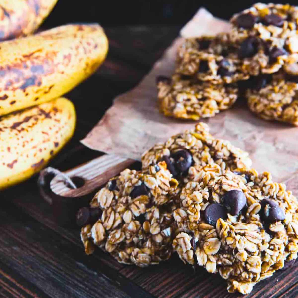 3 ingredient banana oatmeal cookies stacked on top of each other next to a bunch of bananas
