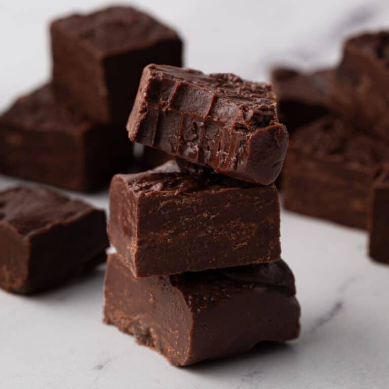 3 ingredient fudge stacked in a tower of 3 with the top piece of fudge with a bite taken out of it to show the texture.