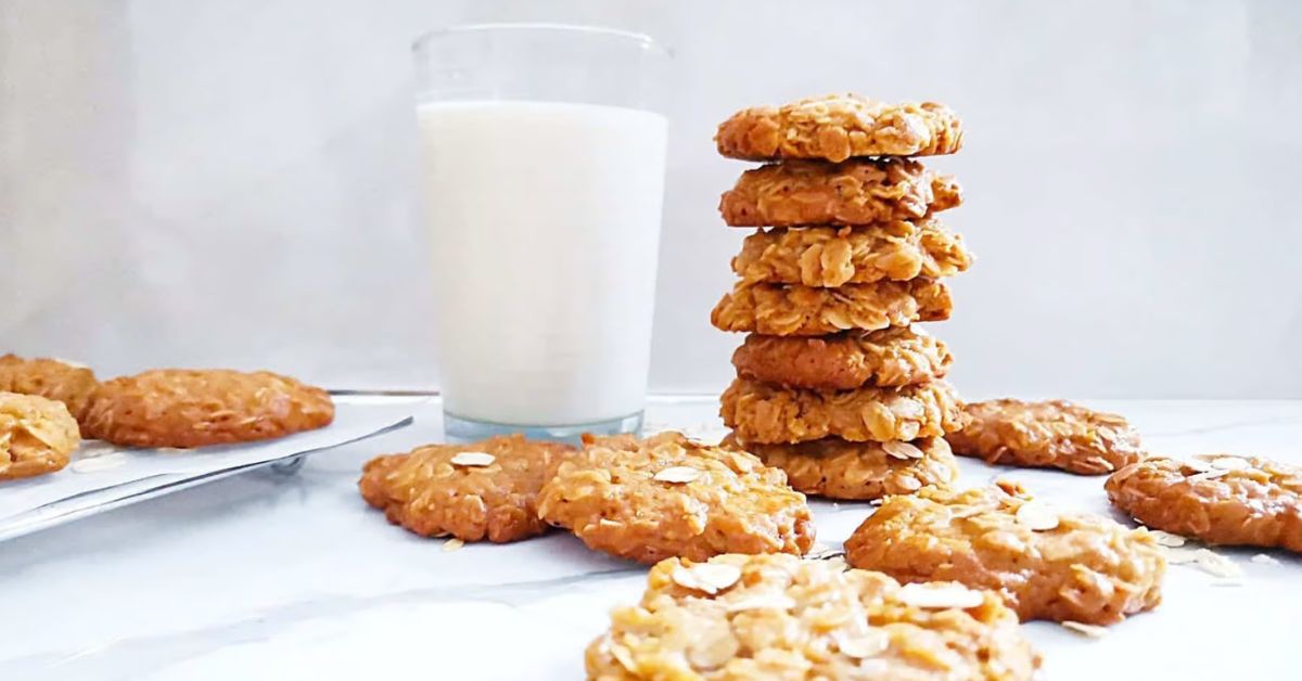 3 ingredient oatmeal cookies made with oatmeal, tahini and honey stacked next to a glass of milk.