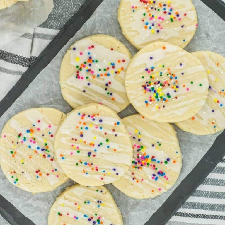 3 ingredient sugar cookies piled on a plate with parchment paper under it