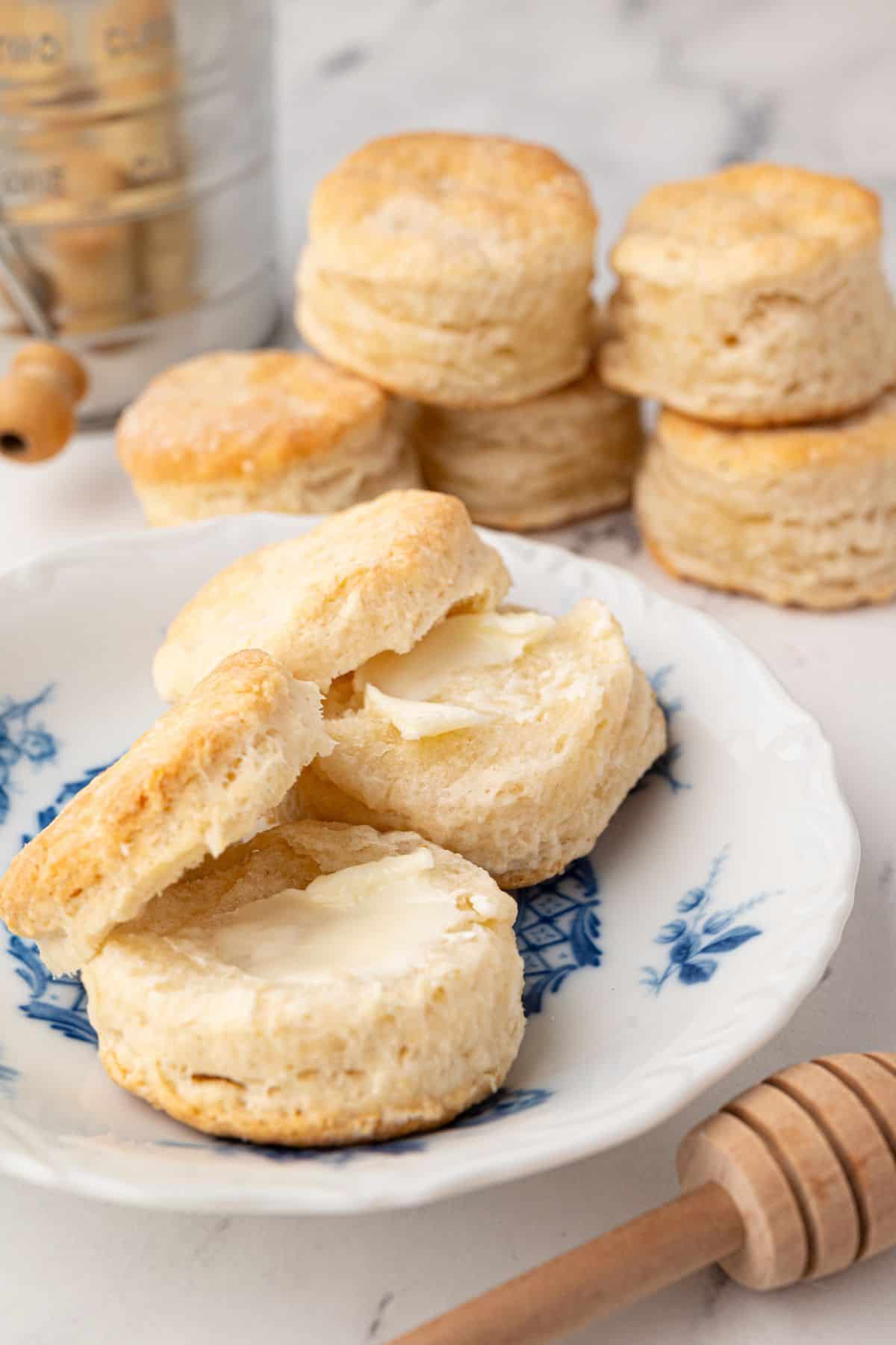 A close-up of biscuits split open with butter melting inside, served on a decorative plate.