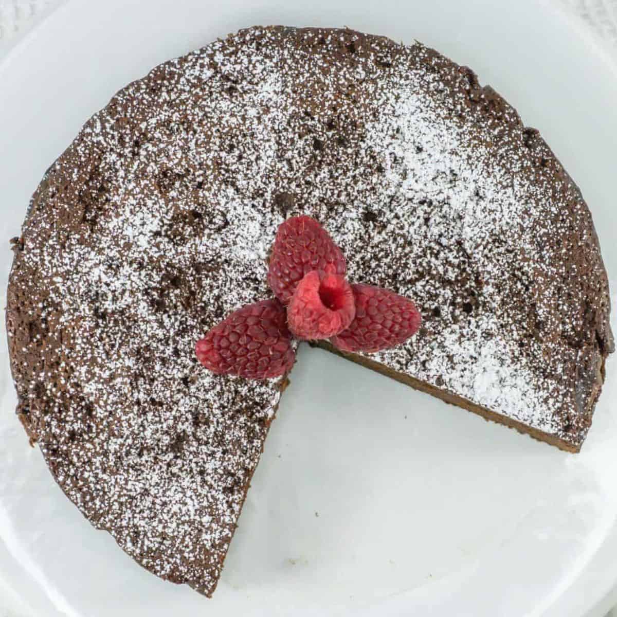 flourless chocolate cake dusted with powder sugar and decorated with raspberries.