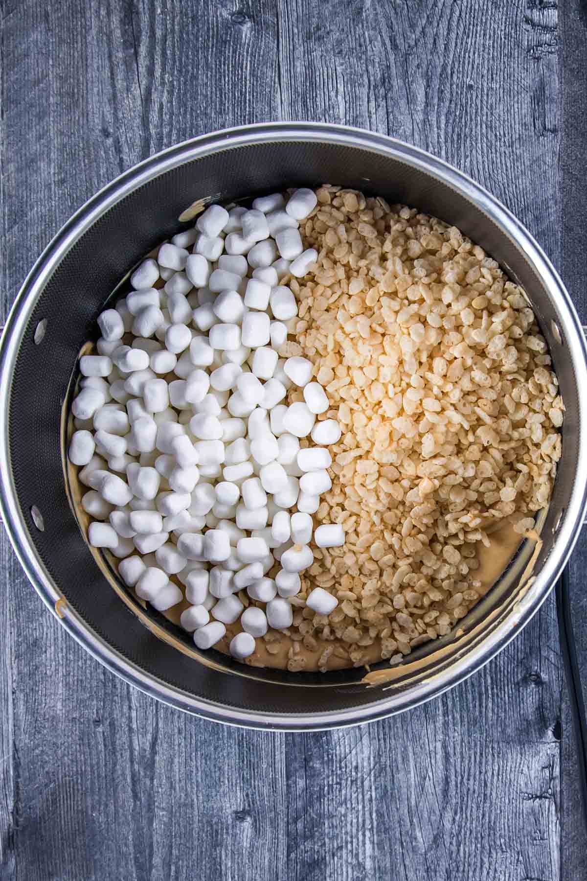 mini marshmallows and rice krispies cereal added to the melted mixture of white chocolate chips and creamy peanut butter in a large pot