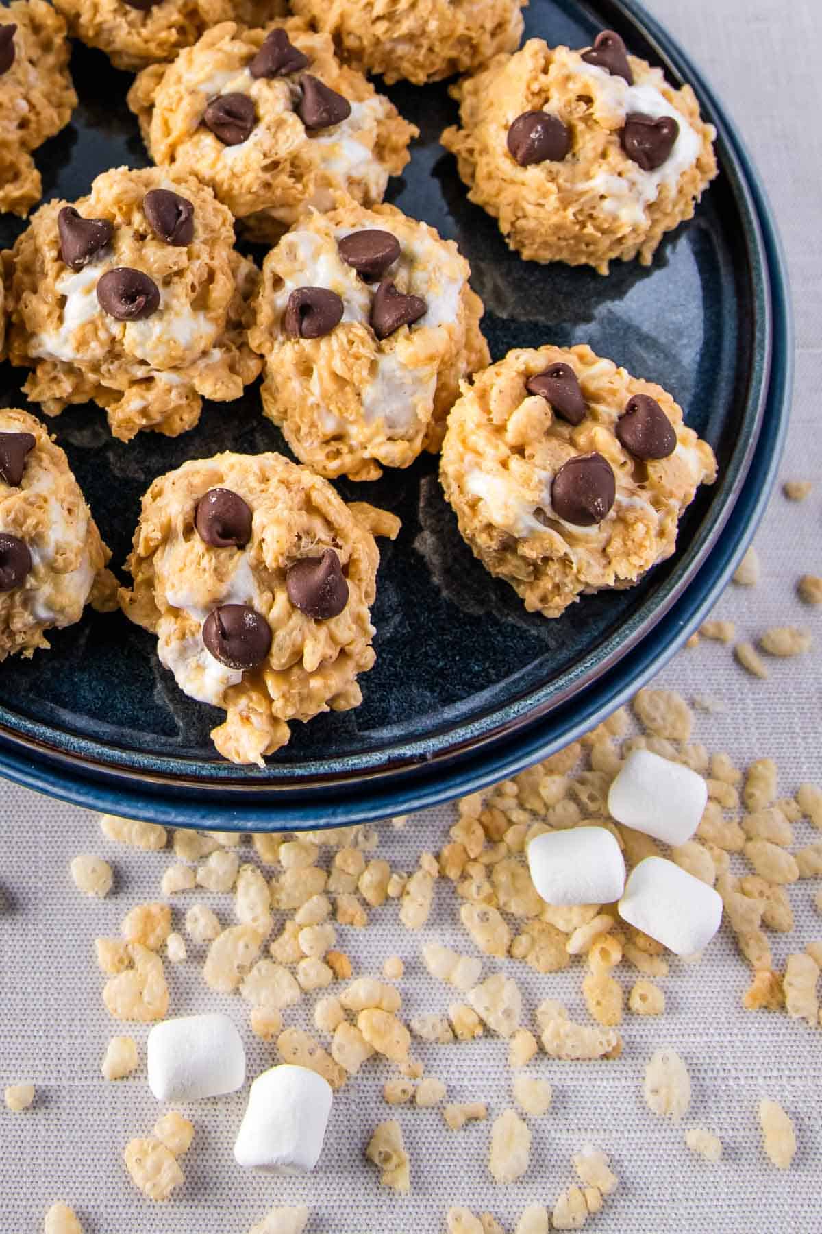 avalanche cookies arranged on a dark plate, with some rice cereal and marshmallows scattered around