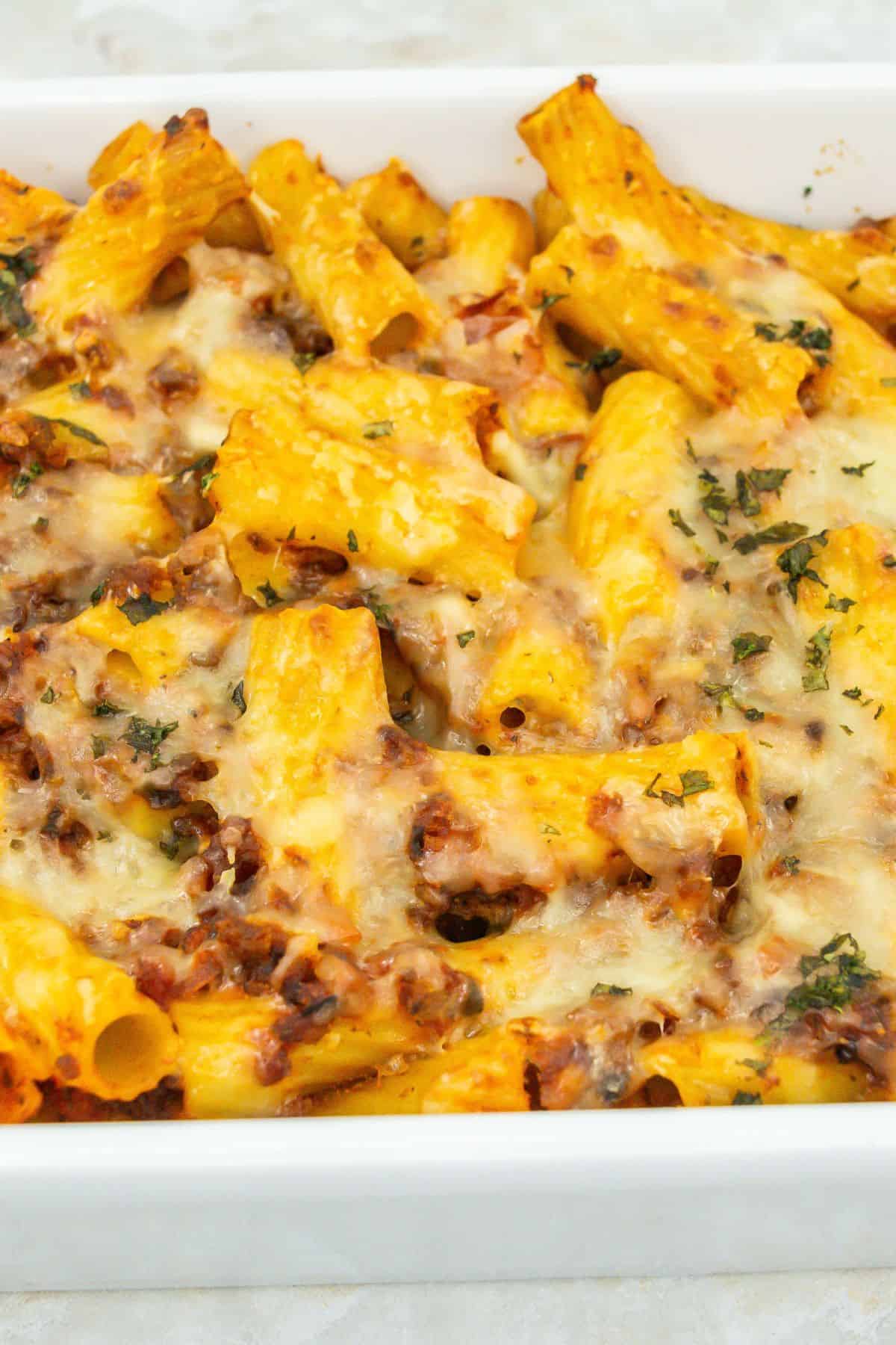 Freshly baked casserole: Baked rigatoni with golden, bubbling cheese and garnished with herbs.