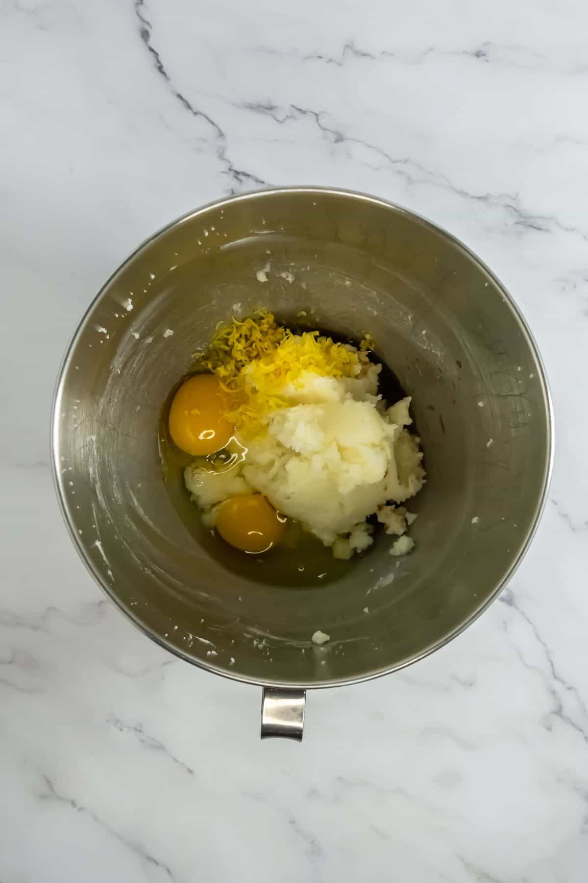 Mixing bowl with eggs, lemon zest, and sugar, ready for batter preparation.