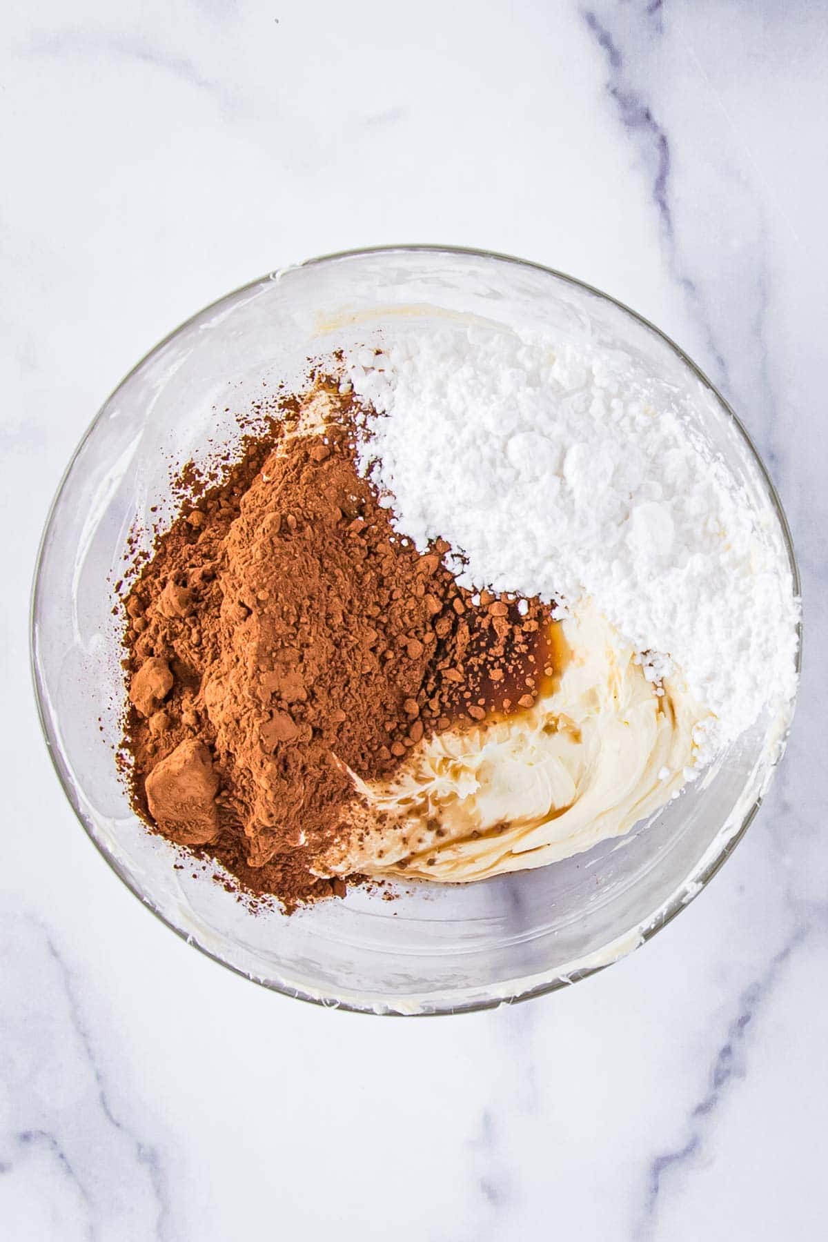 powdered sugar, cocoa powder, and vanilla extract added to smoothed cream cheese in a bowl