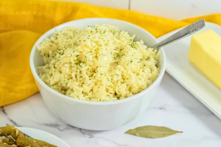 Butter rice in a white bowl with a stick of butter next to it and a yellow napkin