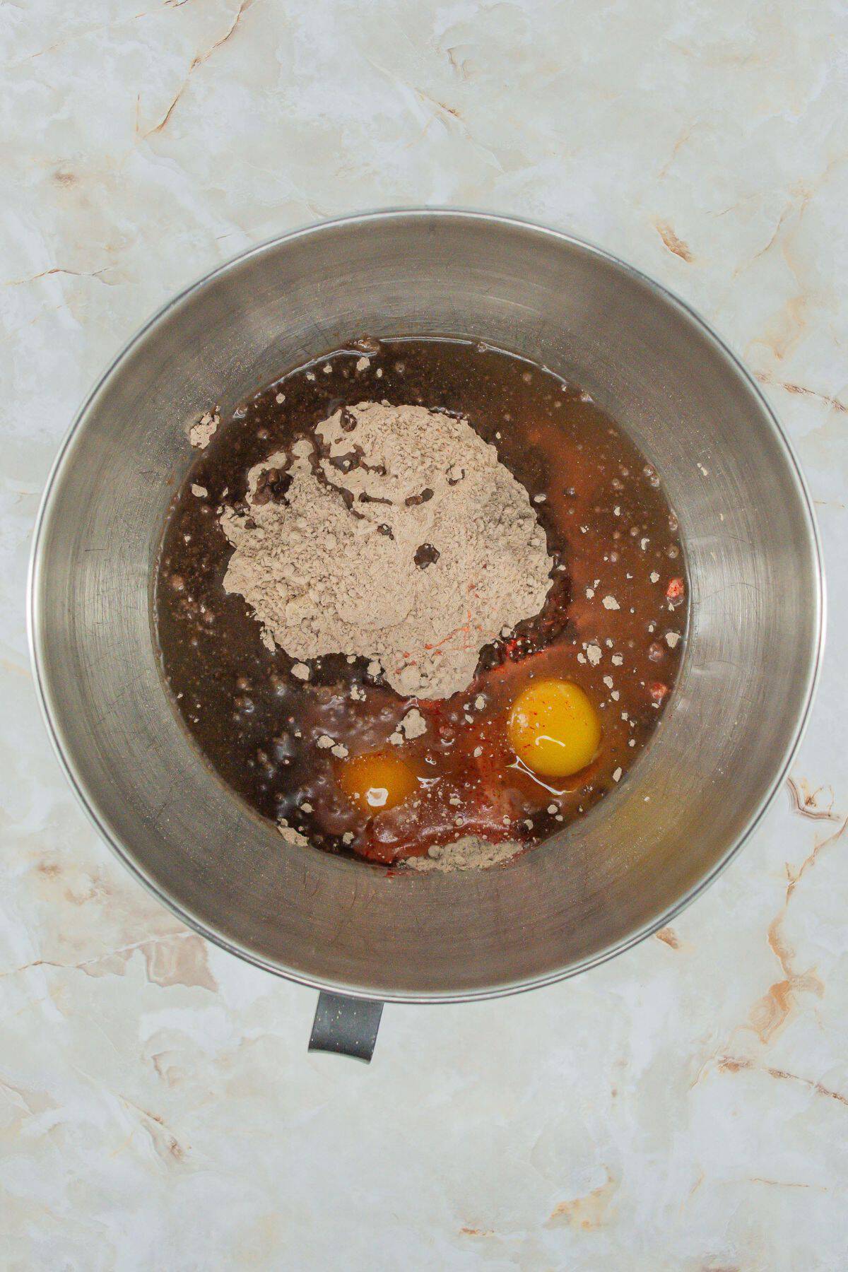 A mixing bowl containing the initial ingredients for the cookie dough—red velvet cake mix, eggs, and oil—before being combined.