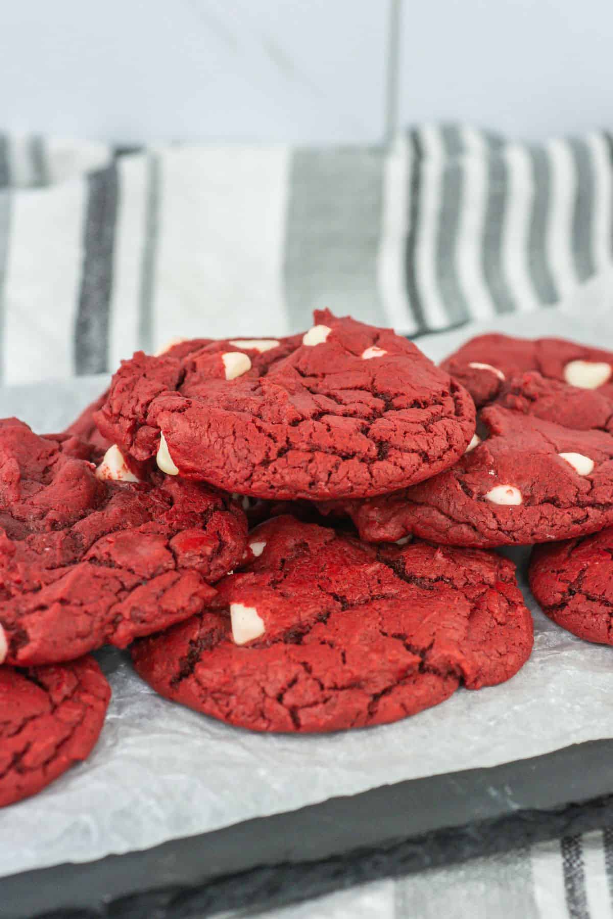 A plate of the baked red velvet cookies, highlighting their crackly top and soft texture, with white chocolate chips standing out beautifully against the red hue.