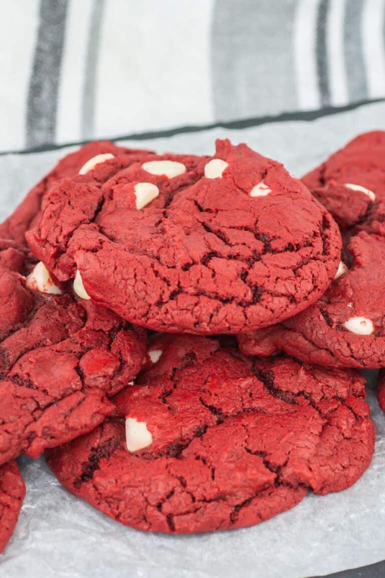 A stack of cake mix cookies with white chocolate chips, placed on parchment paper.