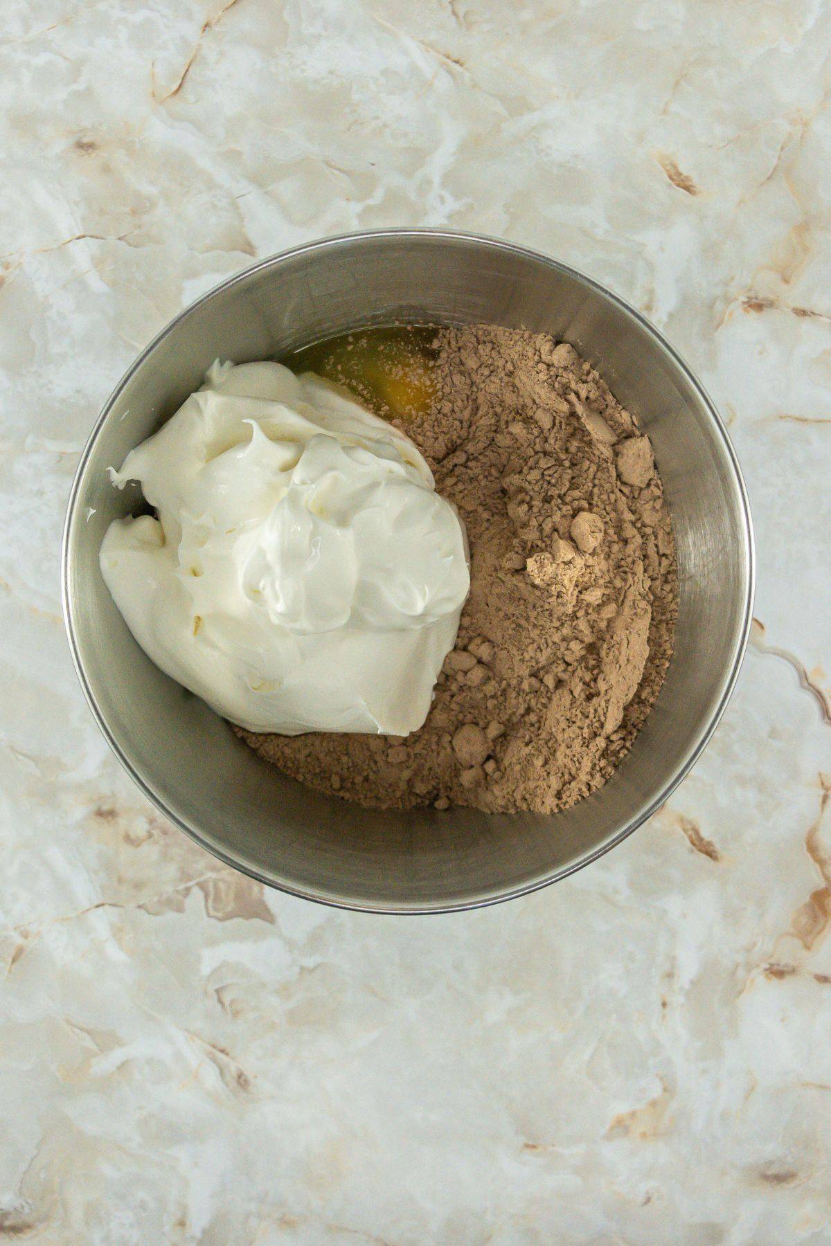 A mixing bowl containing cake mix, Cool Whip, and eggs. The ingredients are ready to be combined into a soft dough.