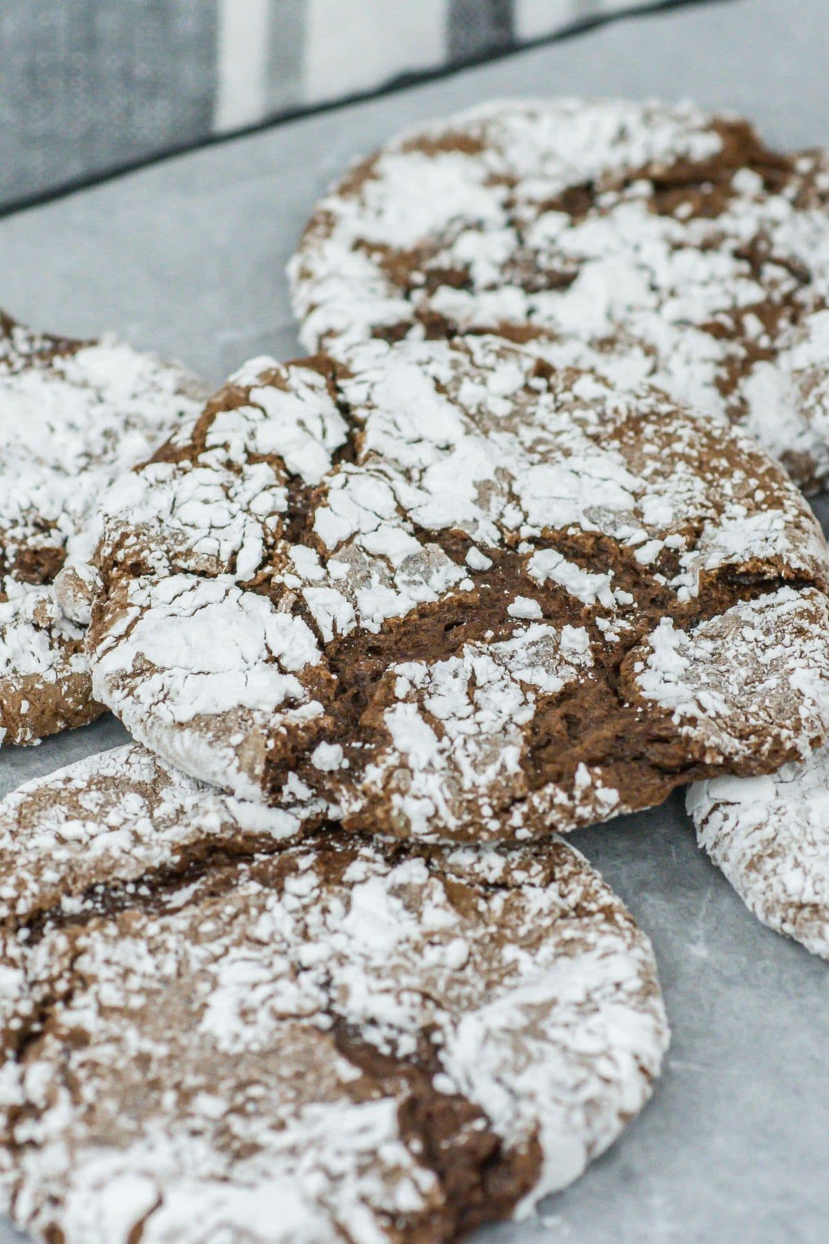 A close-up of chocolate crinkle cookies showing the distinct cracks, powdered sugar coating, and fudgy chocolate texture peeking through.