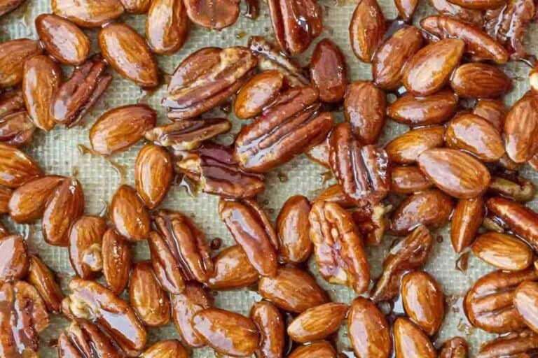 Overhead shot of the sticky Candied Nuts pecans and almonds spread on a baking sheet