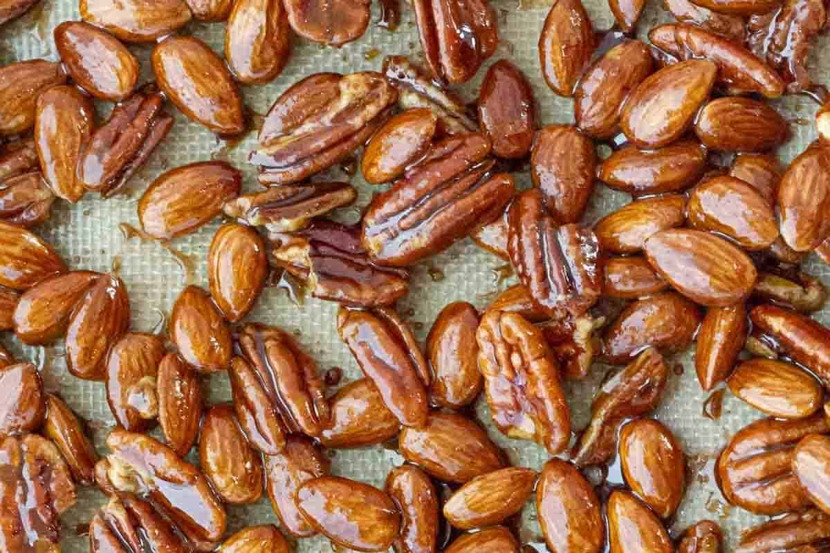 Overhead shot of the sticky candied pecans and almonds spread on a baking sheet