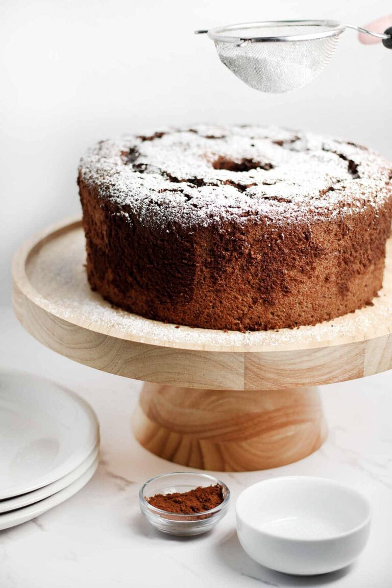 chocolate angel food cake being dusted with powdered sugar