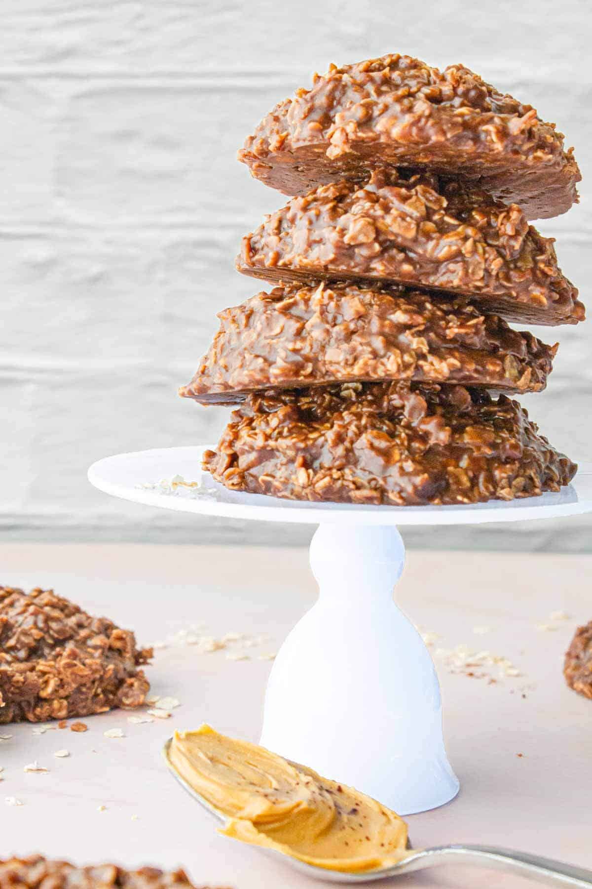 A dramatic side view of stacked cookies with a spoonful of peanut butter in the foreground.