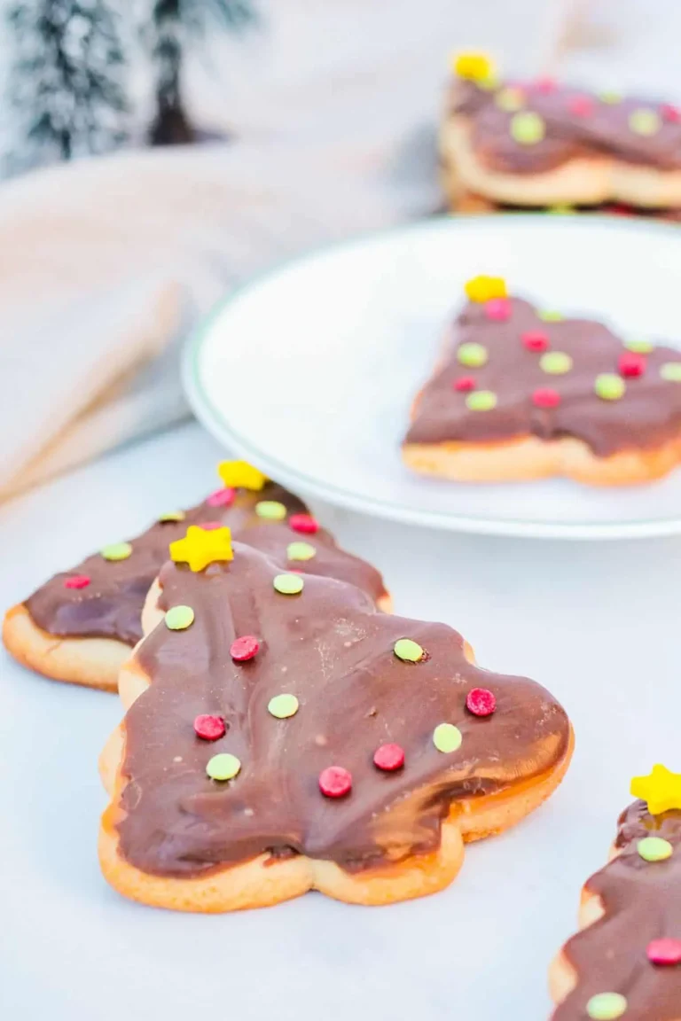 Christmas tree shaped cut out cookies topped with caramel and chocolate with sprinkles