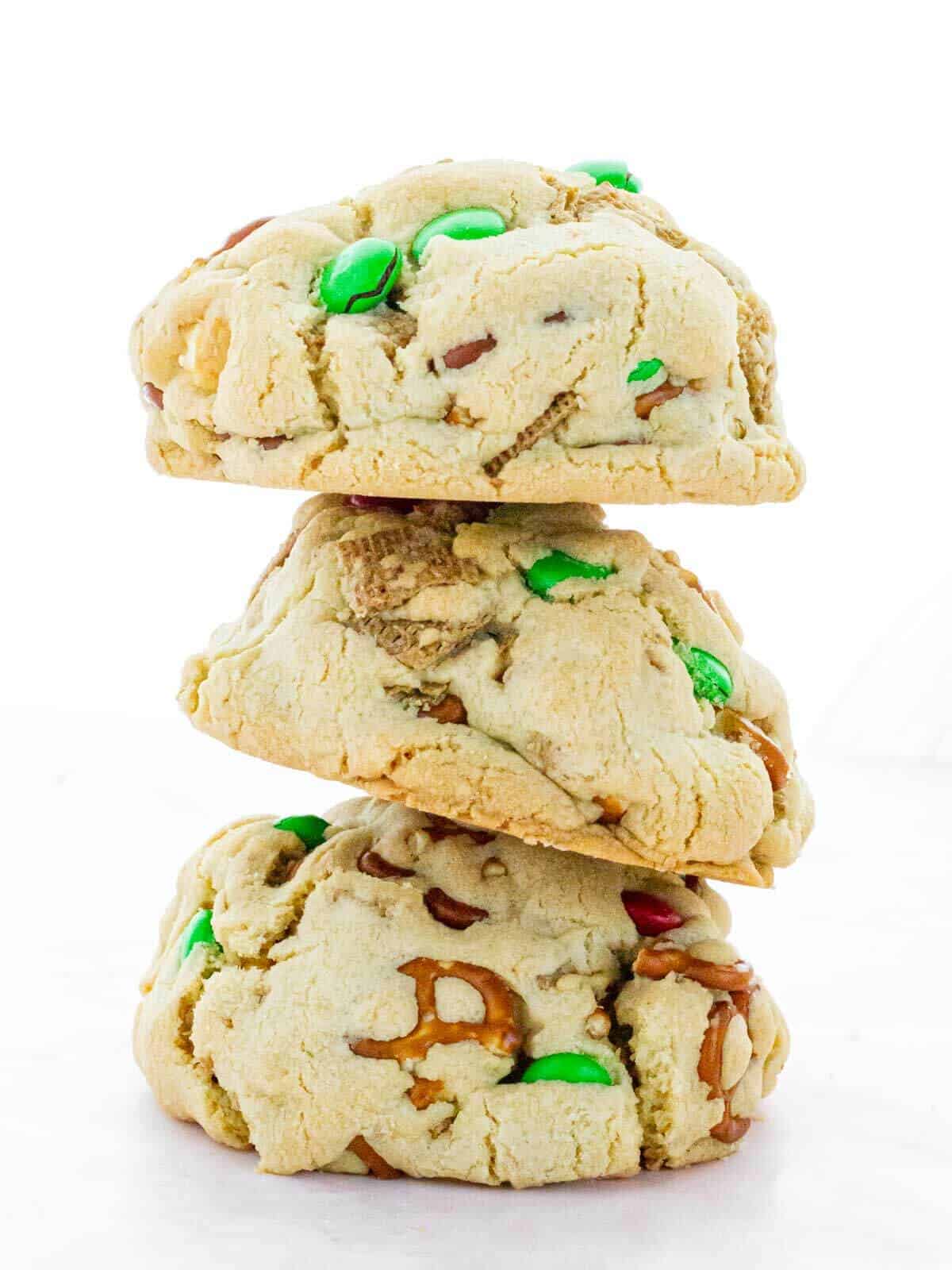 A stack of three Christmas Chex Mix cookies, highlighting their thick, chunky texture with colorful mix-ins