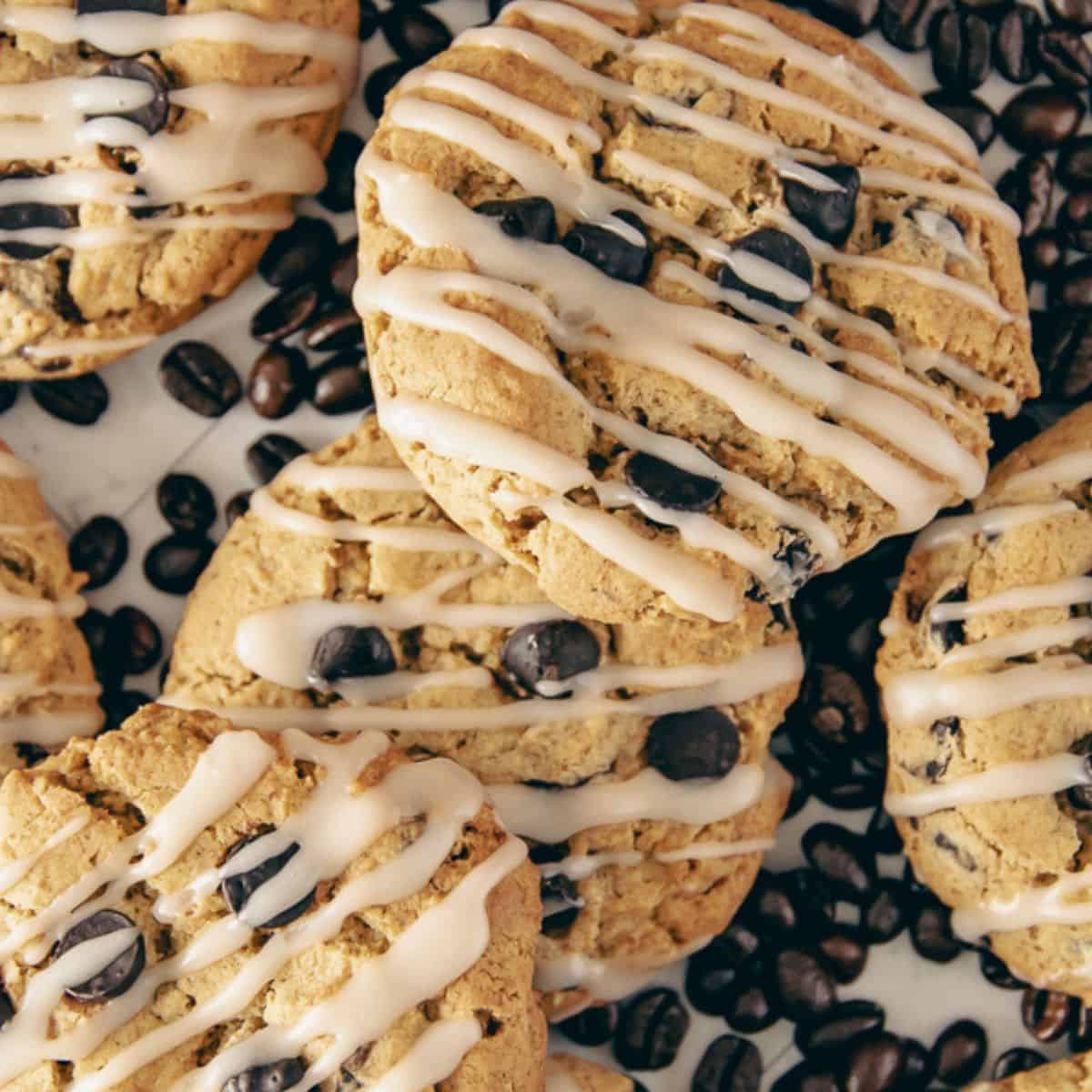 A detailed view of freshly baked coffee cookies topped with a creamy glaze, laid on a bed of whole coffee beans for an extra bold aesthetic.