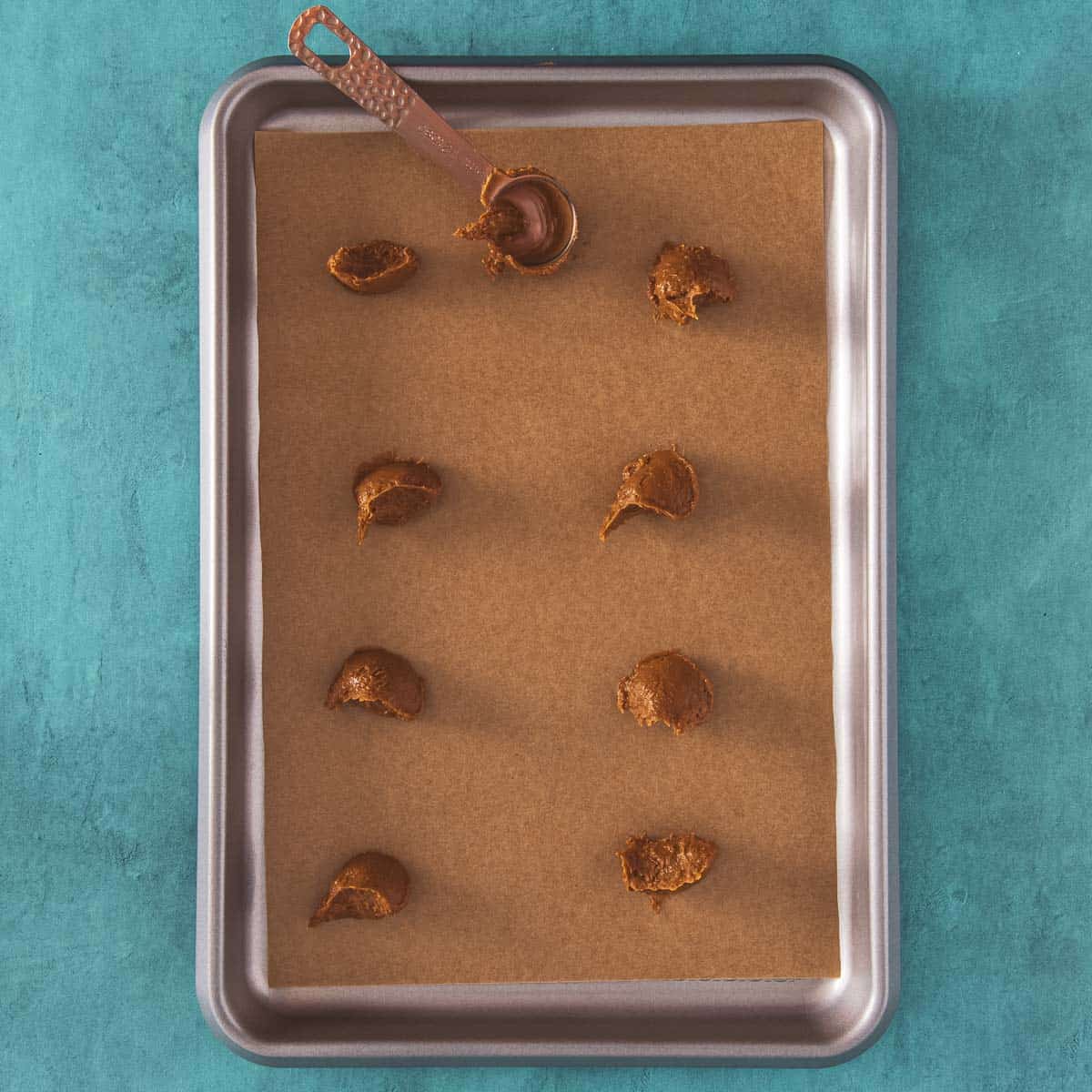 Dollops of Biscoff spread on a lined baking sheet.