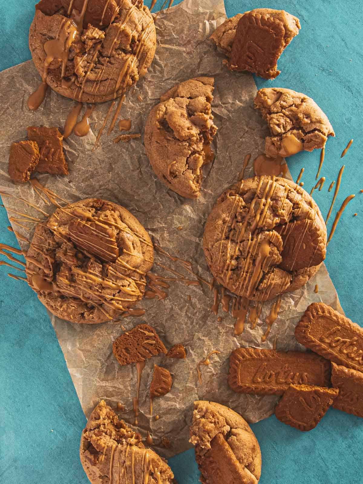 A parchment-lined surface with cookie butter cookies drizzled in melted Biscoff spread.