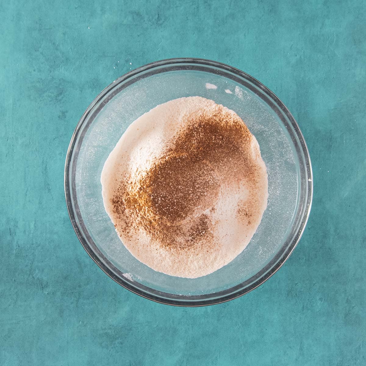 – Flour and spices mixed in a glass bowl.