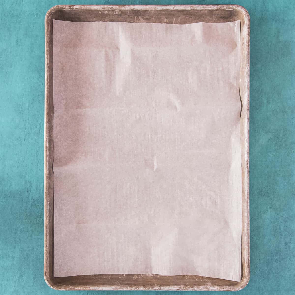 Parchment paper covering a baking sheet, prepped for cookies.