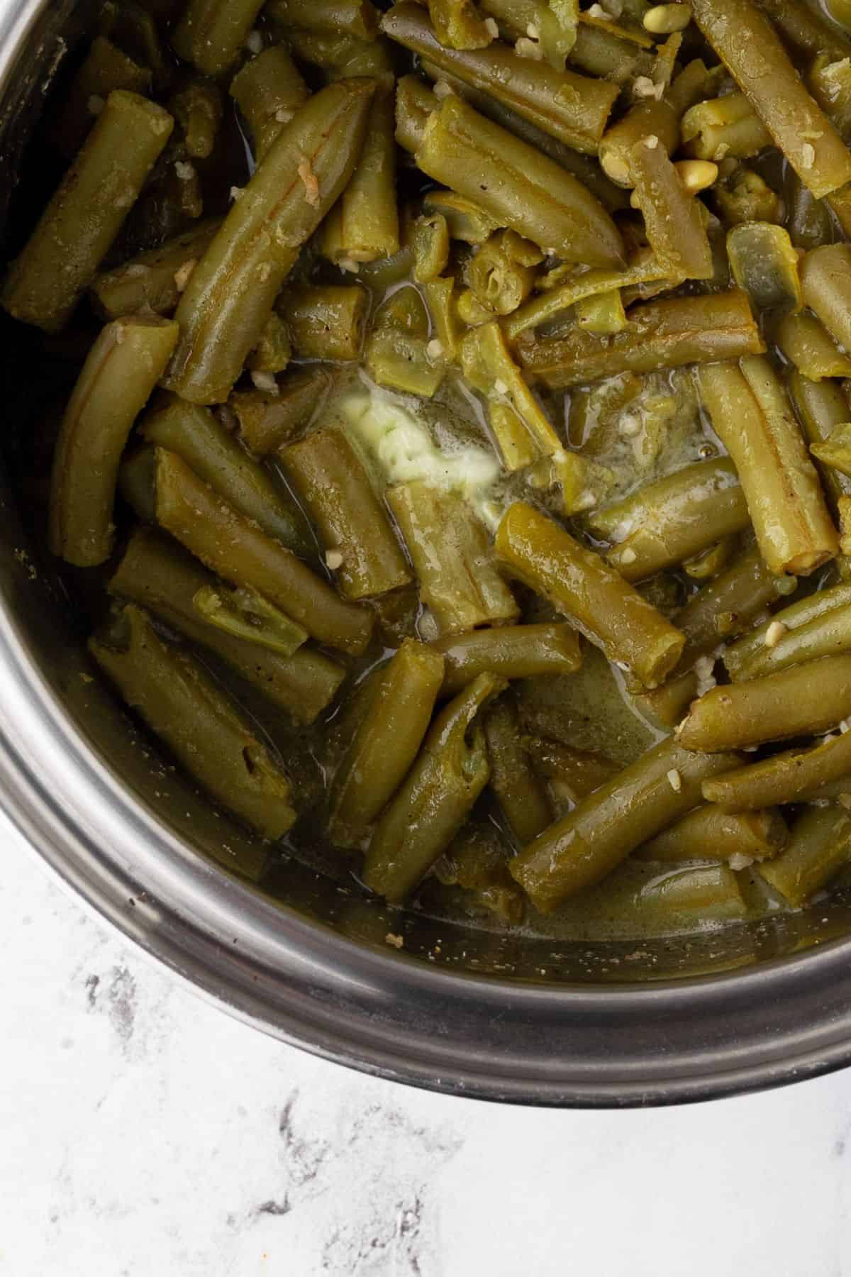 Overhead view of a pot of cooked green beans in their flavorful sauce.