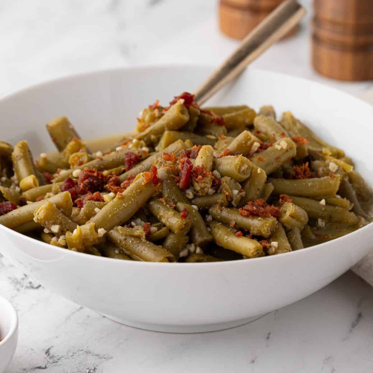 cooked canned green beans in a white bowl with a fork
