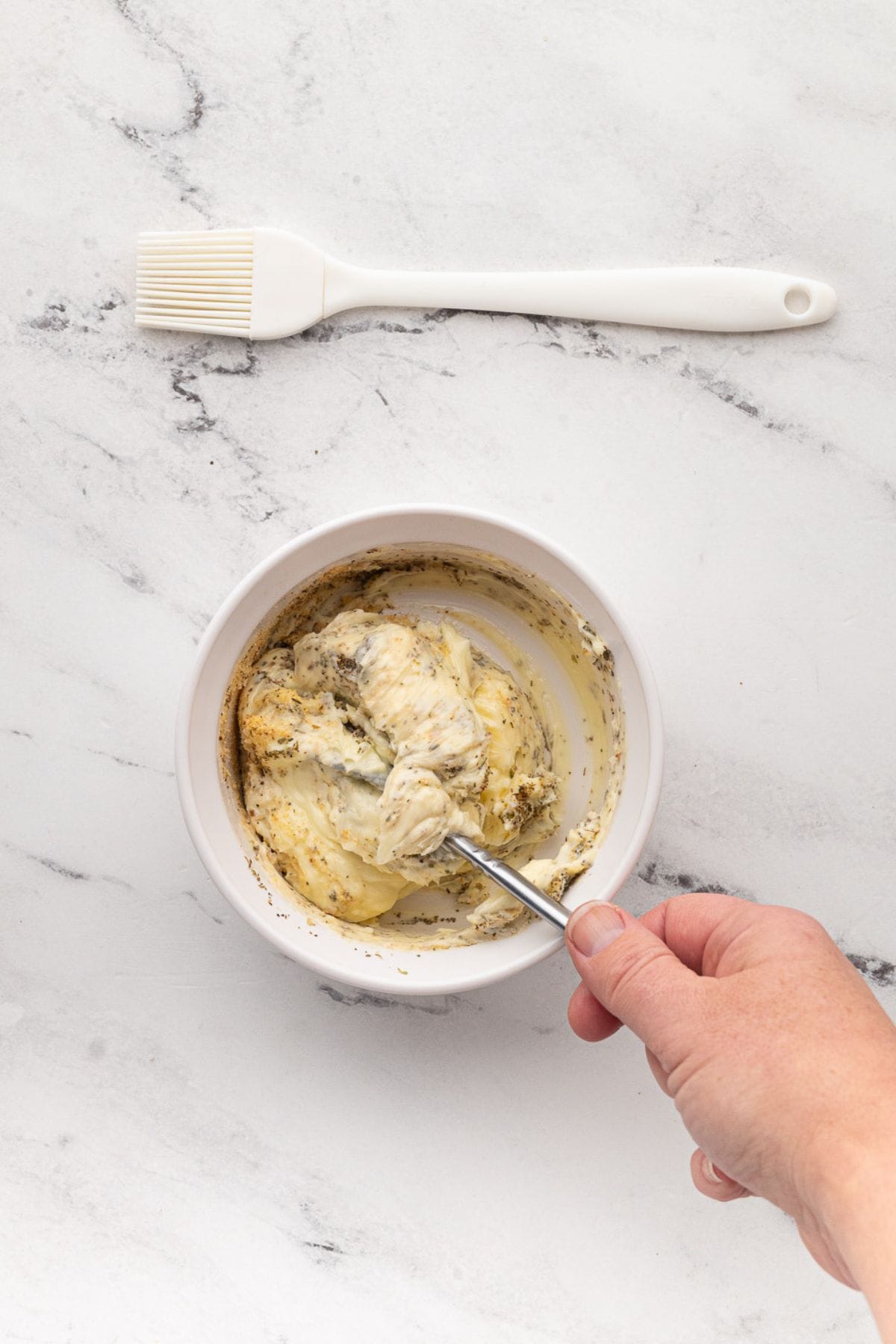 Mixing butter with seasonings in a bowl to create garlic spread.