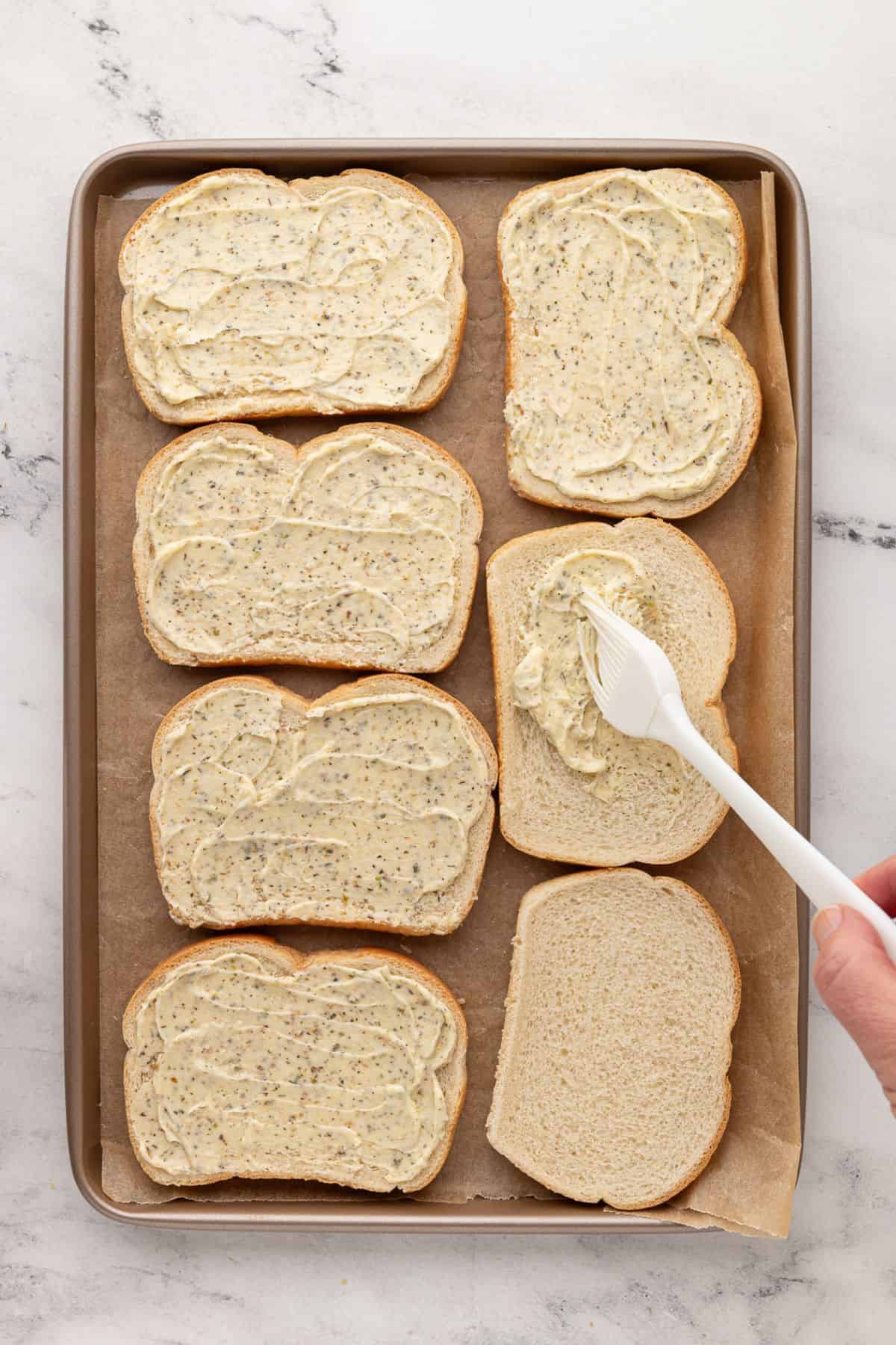 Bread slices evenly coated with garlic-herb butter spread.