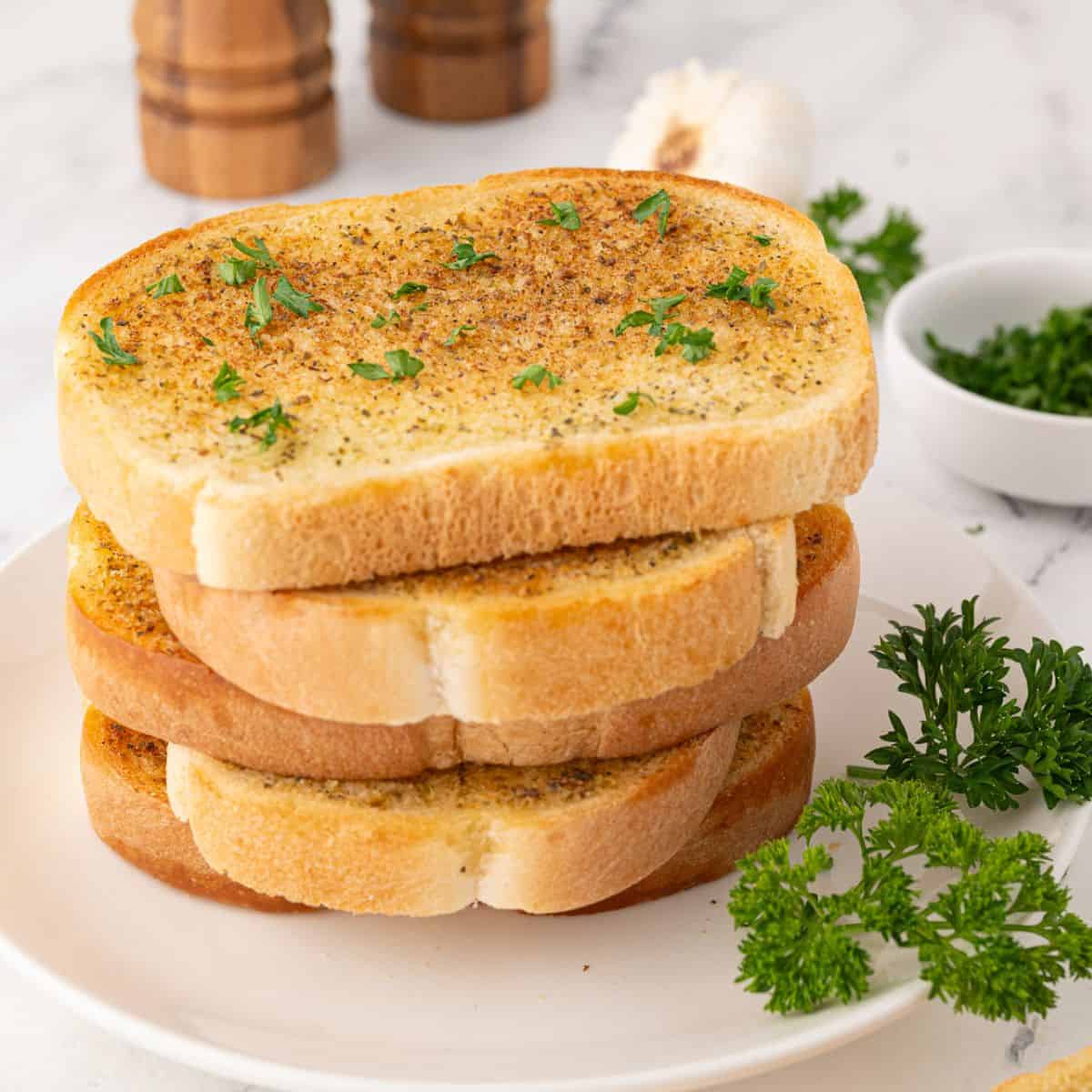 garlic toast on a plate stacked in a pile.