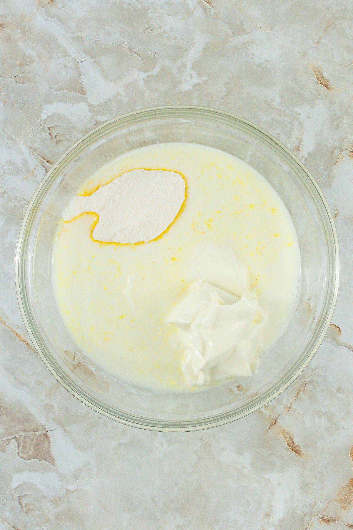 A mixing bowl with milk, pudding mix, and sour cream before mixing.