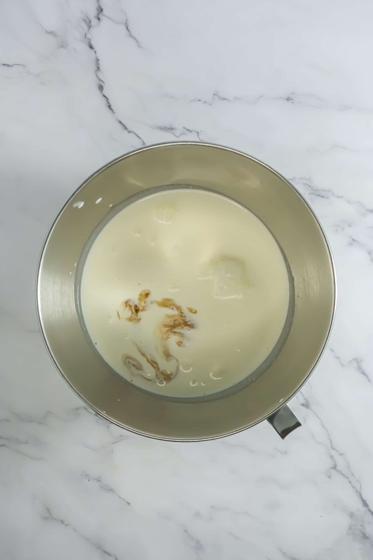 A mixing bowl containing cream and vanilla, ready for whipping.