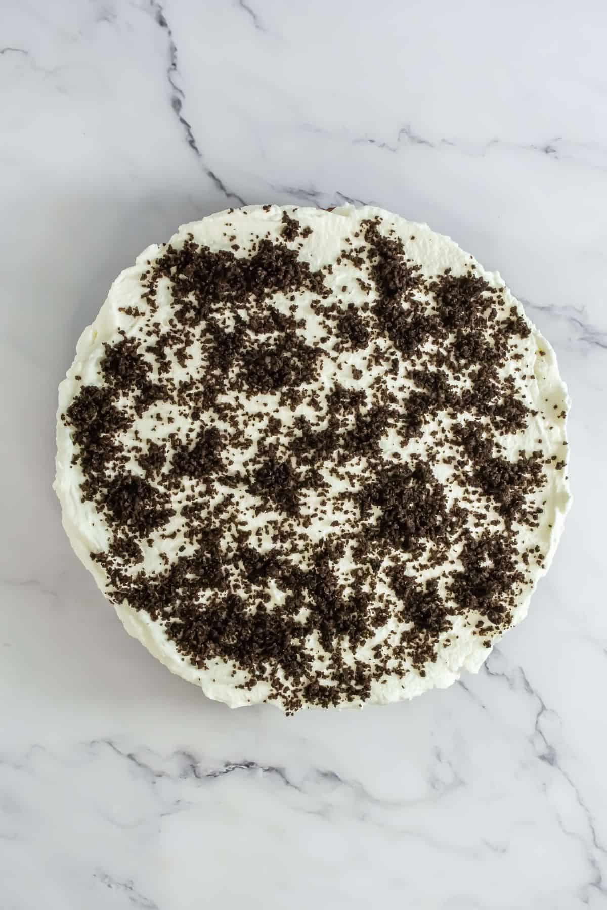 Fully assembled Oreo mousse cake with a whipped cream layer and crushed Oreo topping.