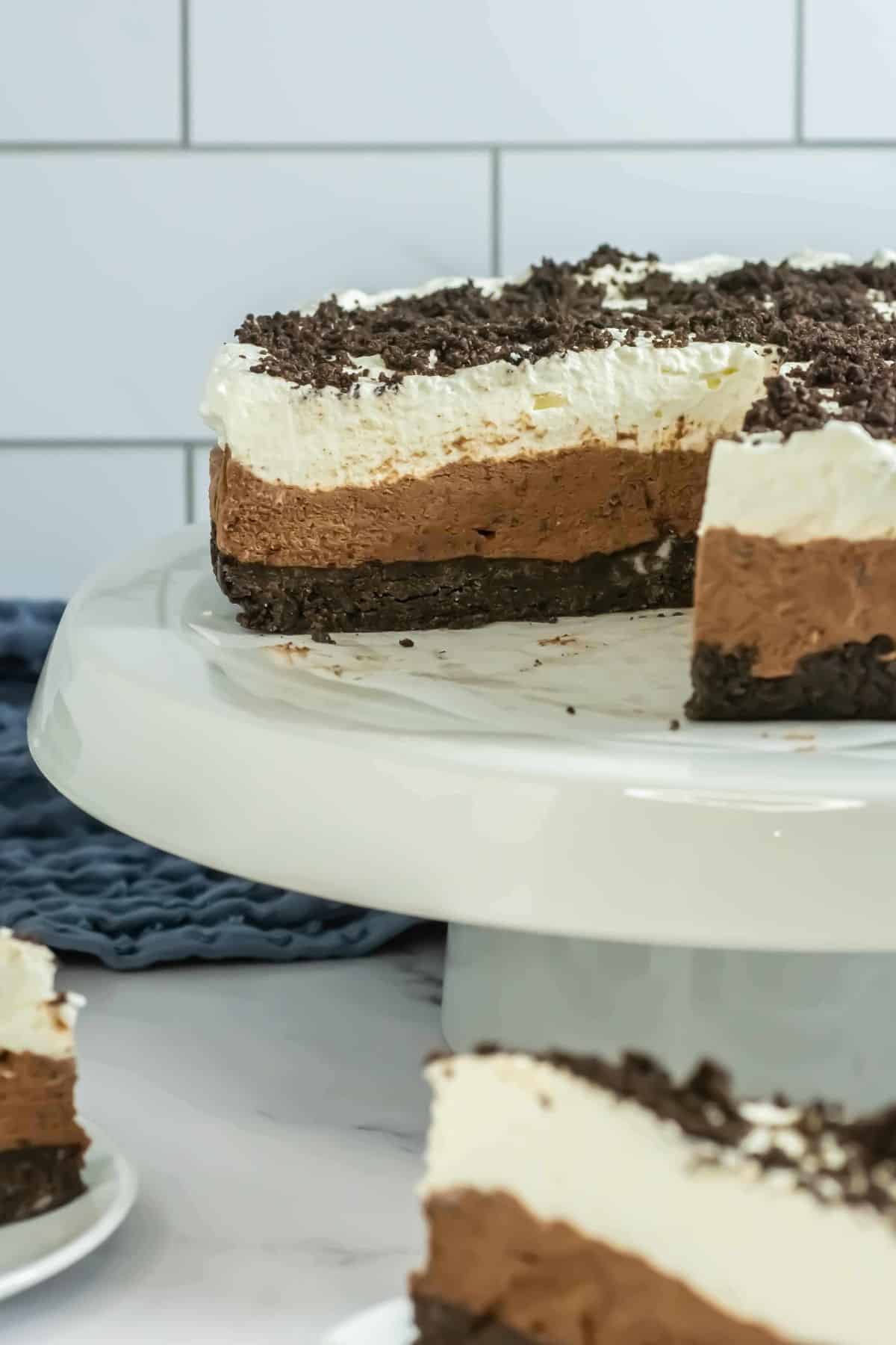 The whole Oreo mousse cake on a cake stand with a slice cut out, showing the layered structure.