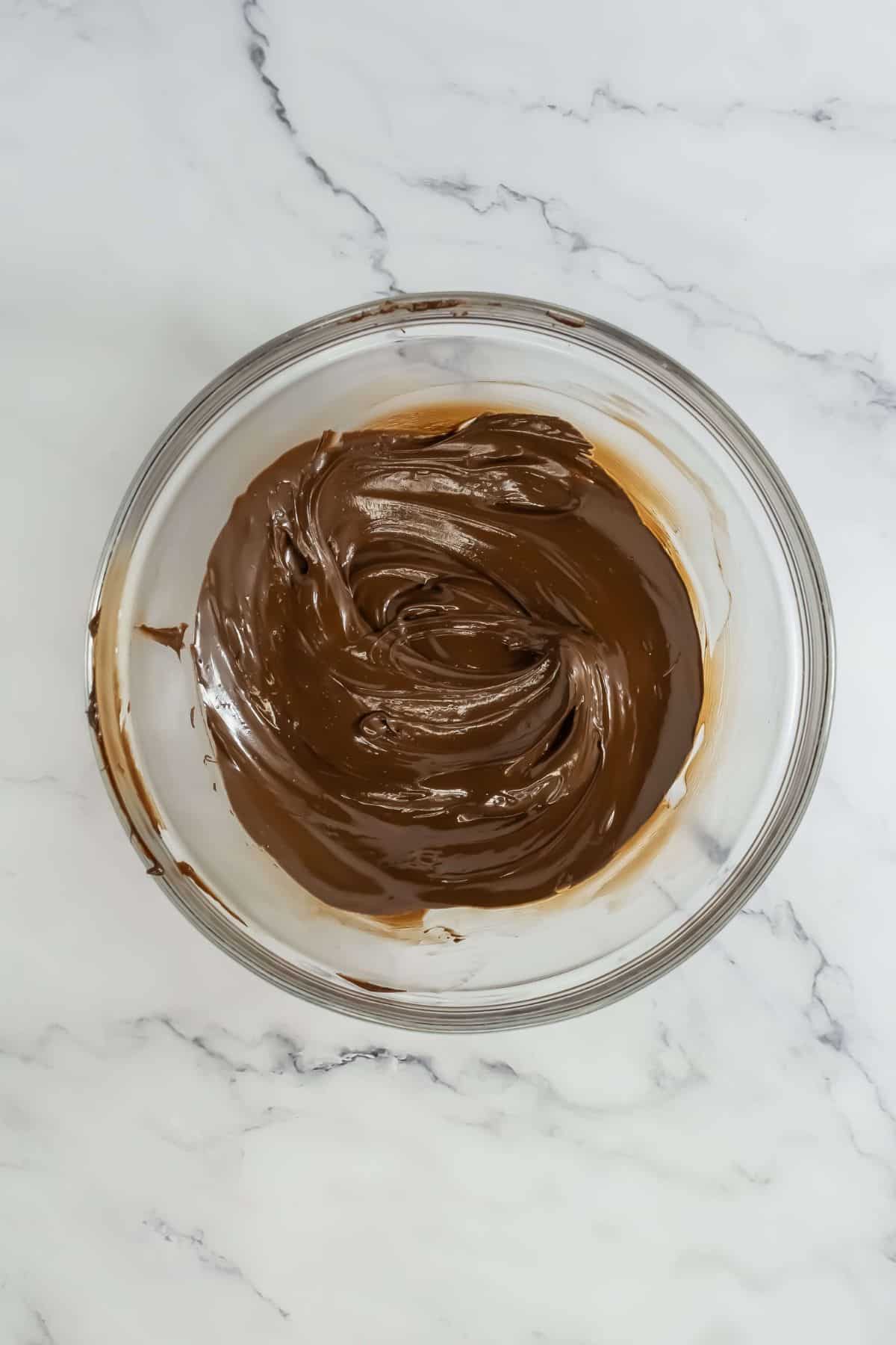 Melted chocolate ganache in a bowl, smooth and glossy for use in the mousse.