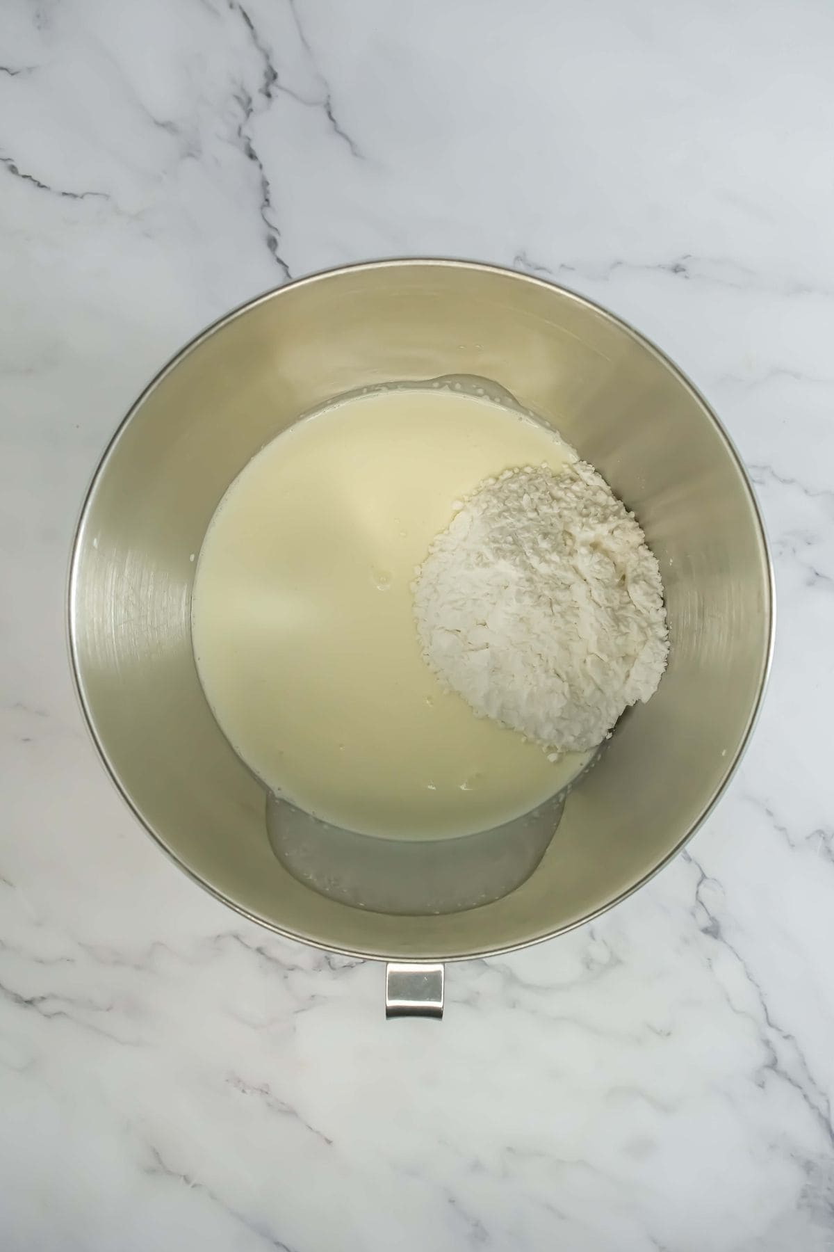 Heavy cream and powdered sugar in a mixing bowl, ready for whipping into the cream layer.