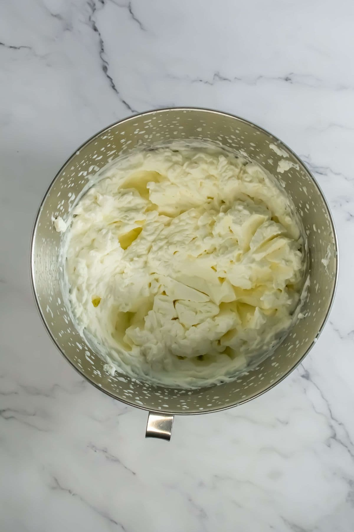 Whipped cream, fluffy and light, prepared for spreading on the mousse cake.