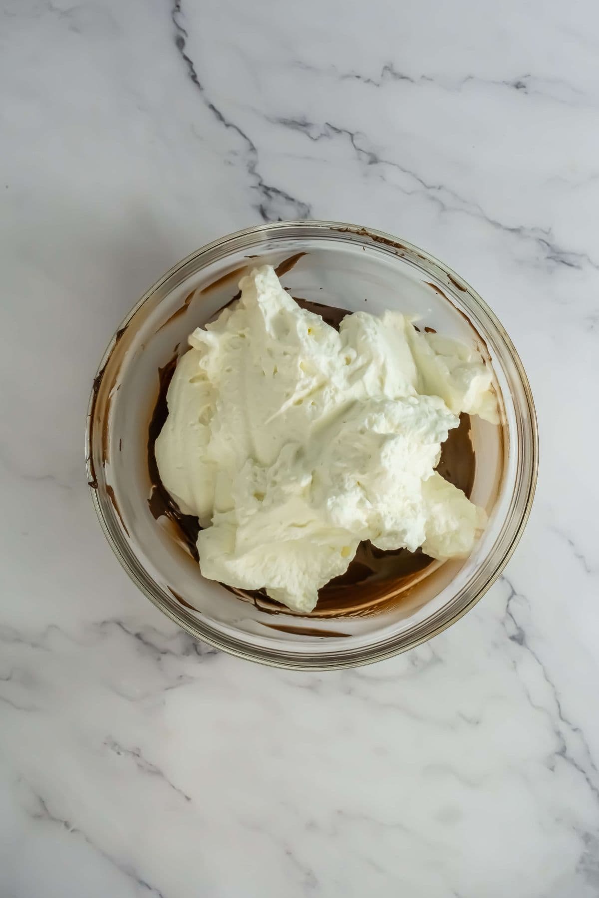 A glass bowl filled with whipped cream topping a layer of chocolate mousse.