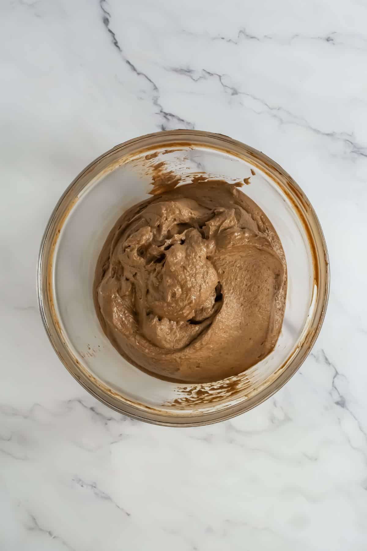 Creamy chocolate mousse mixture in a glass bowl, smooth and ready for layering