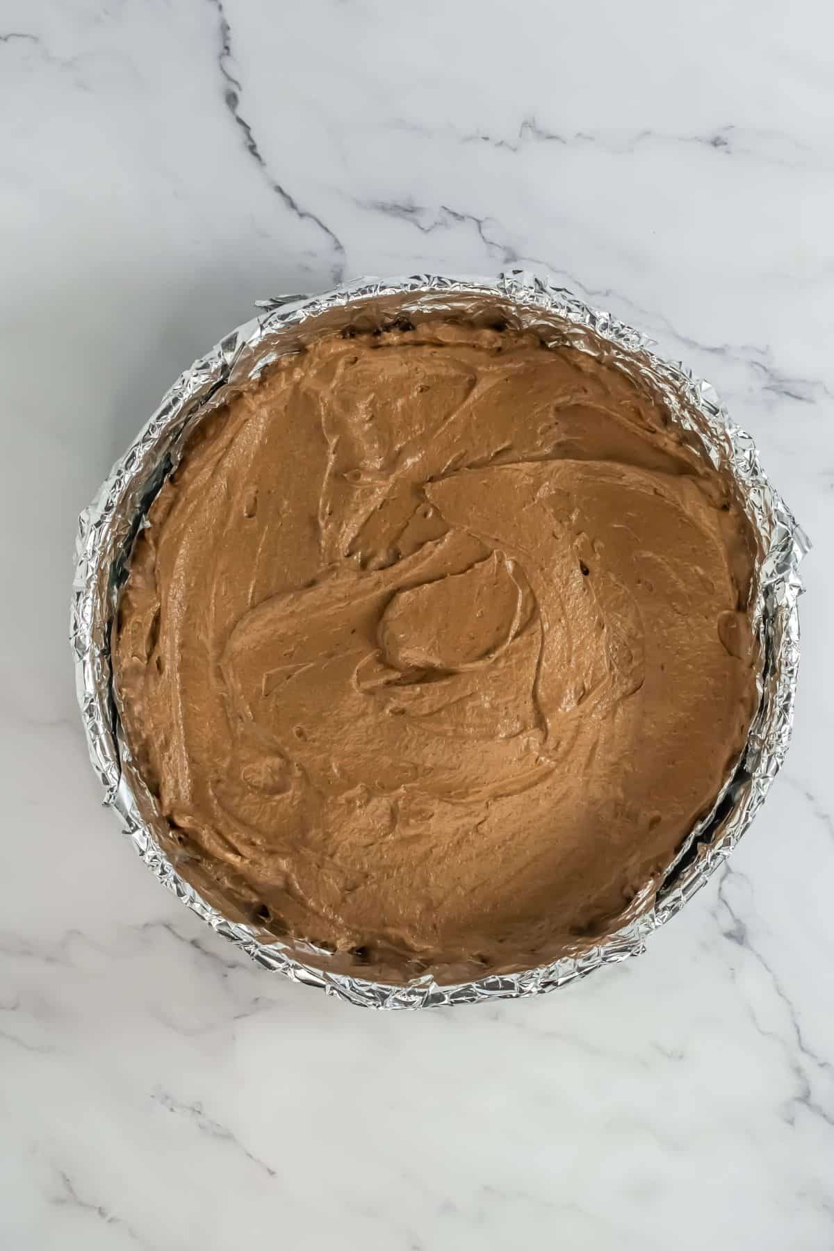 Chocolate mousse layer evenly spread over the Oreo crust in the springform pan.