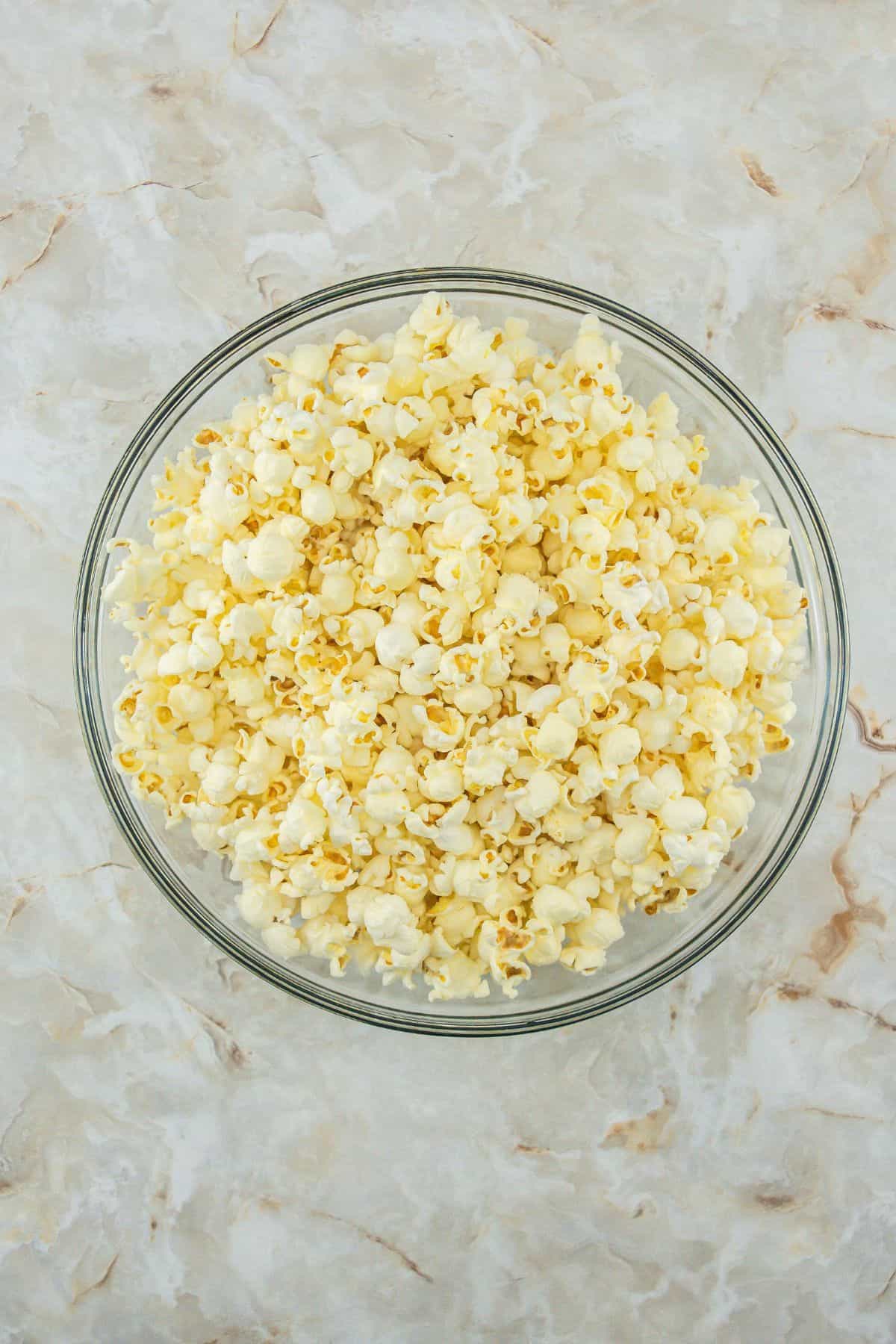 Freshly popped plain popcorn in a glass bowl.