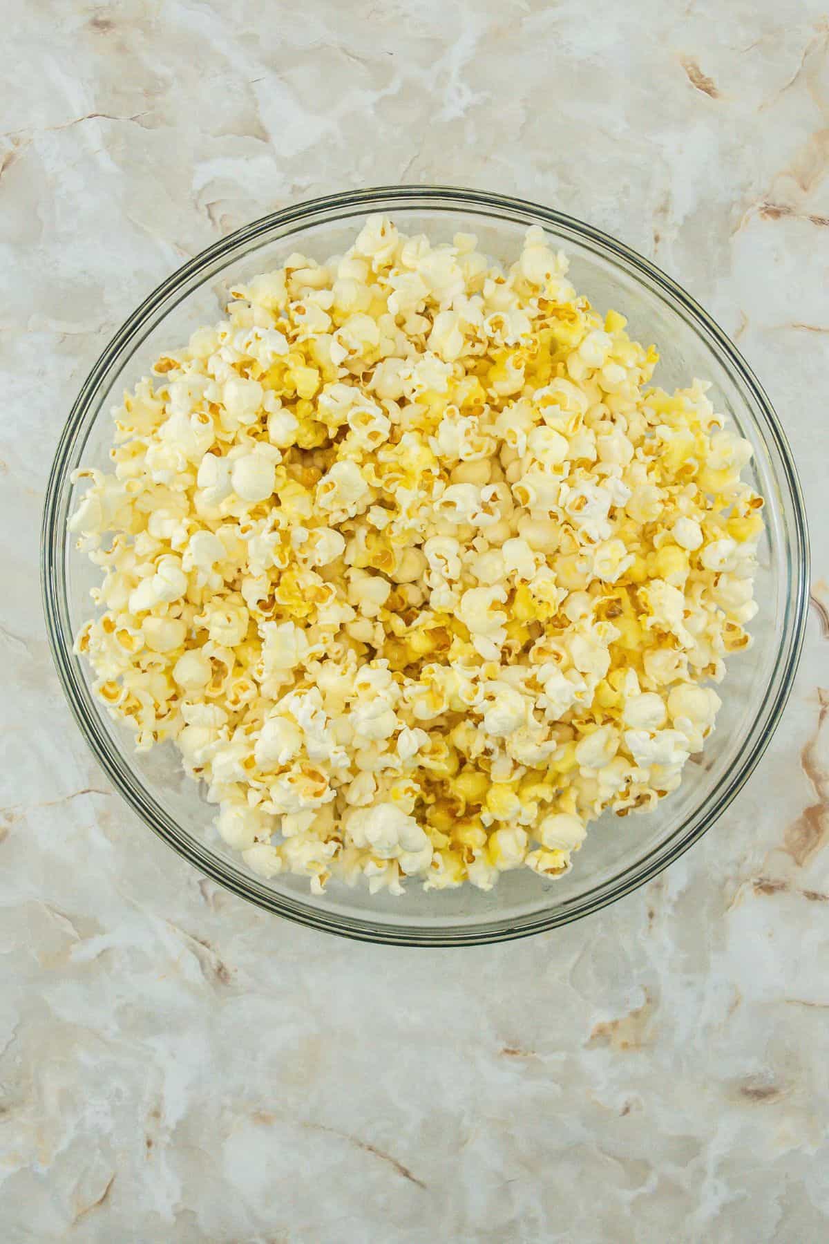 A top-down view of a bowl of plain popcorn.