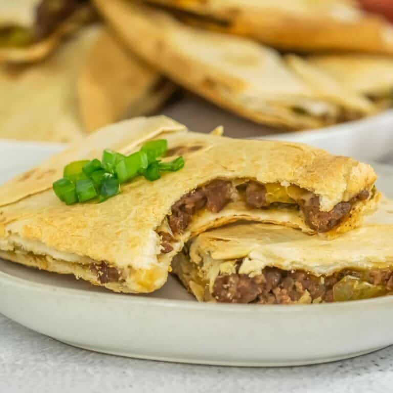 Close-up of a crispy sheet pan quesadilla slice garnished with chopped green onions.