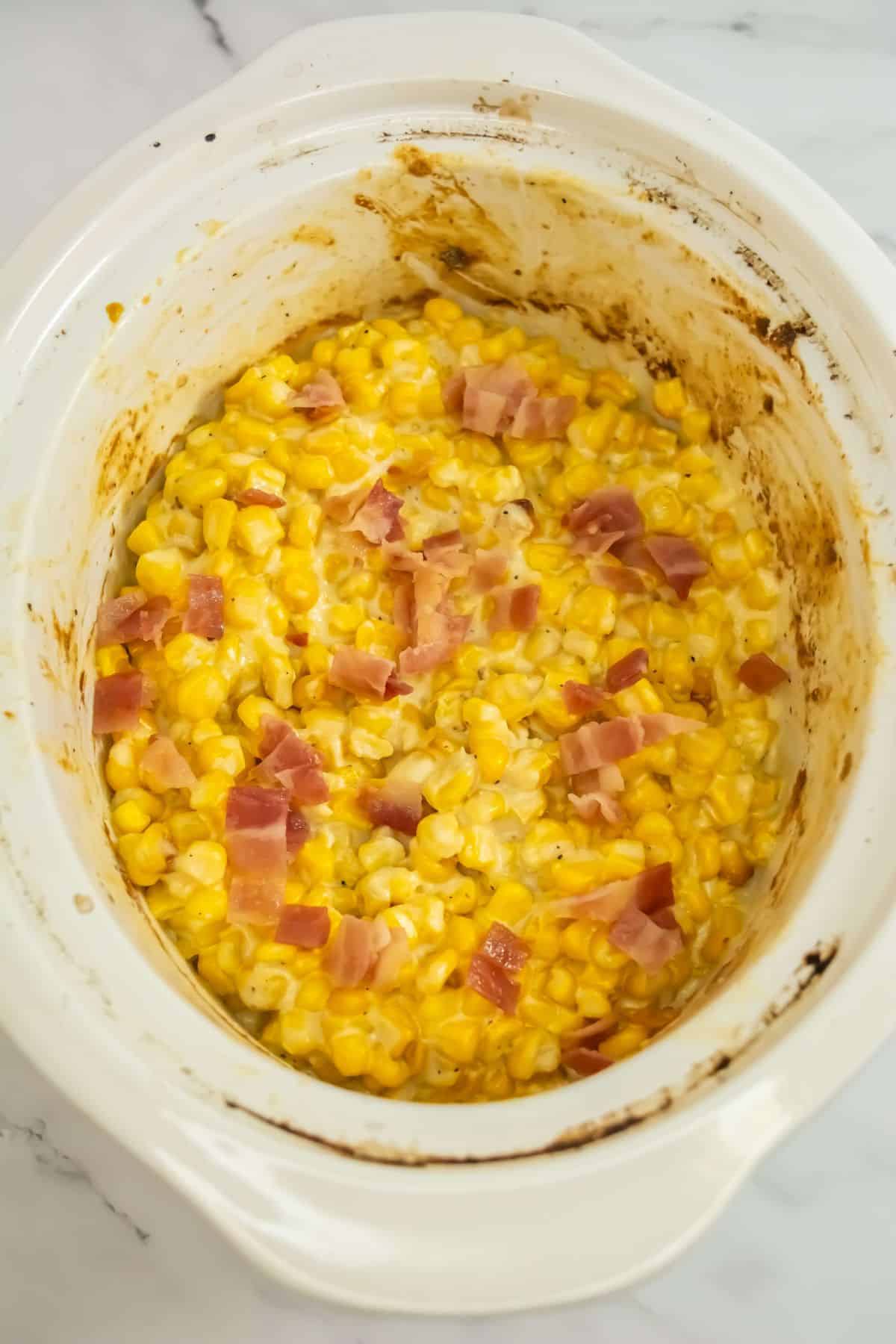 A creamy, cheesy corn mixture finished in the slow cooker, topped with crispy bacon pieces.