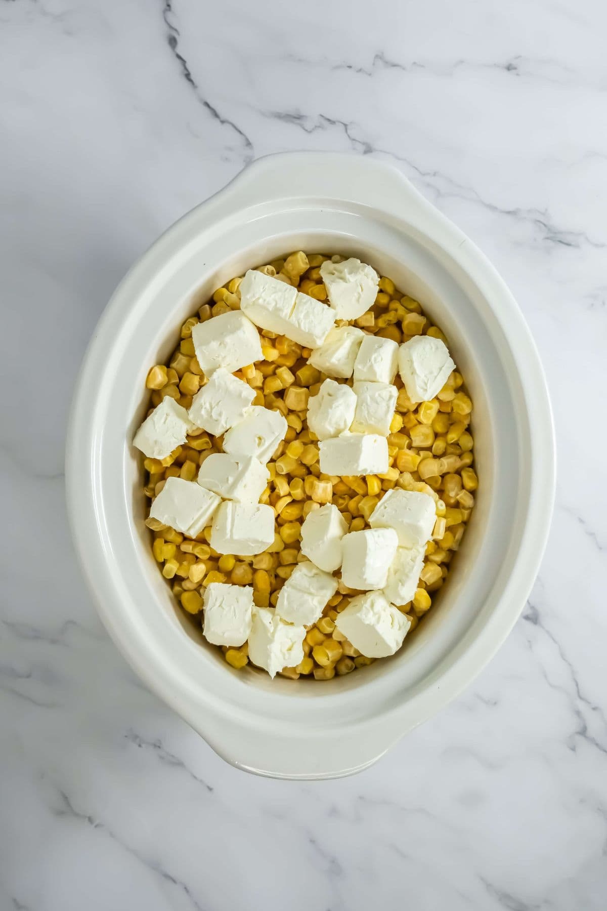 Cubes of cream cheese are scattered over the corn.