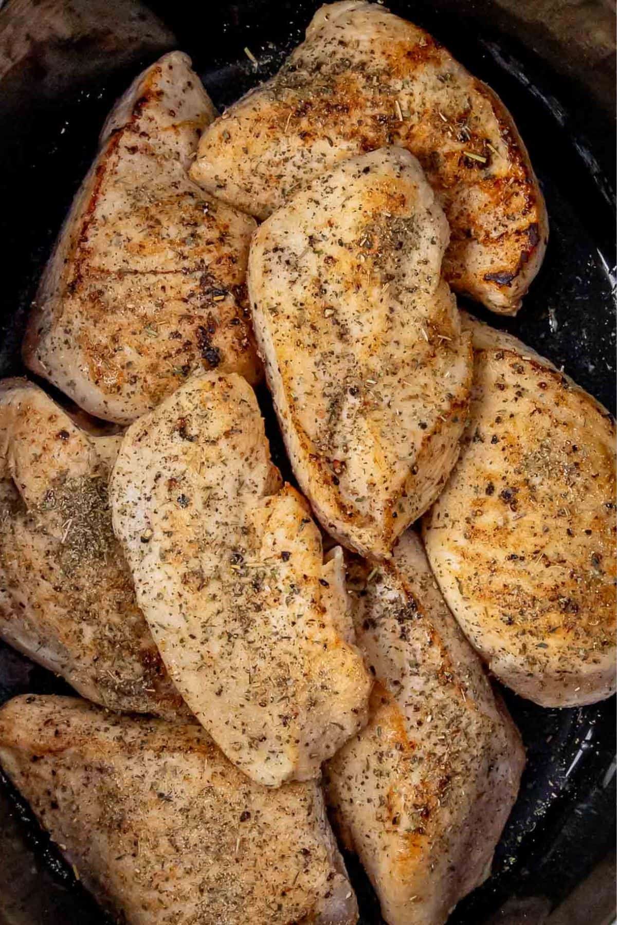 Golden, herb-seasoned chicken breasts layered tightly together in the slow cooker, showcasing a crispy sear and even seasoning.