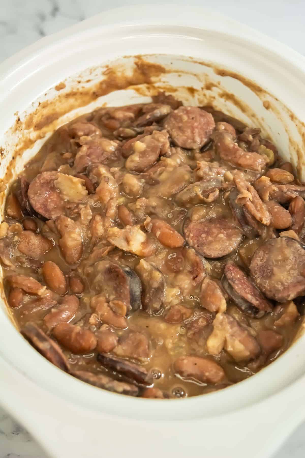Close-up of creamy red beans and sausage in a slow cooker.